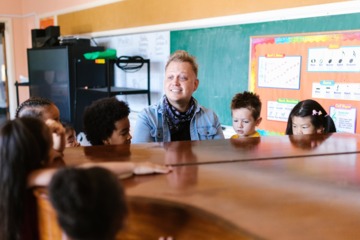 Muziekleraar geeft les aan een groep jonge kinderen